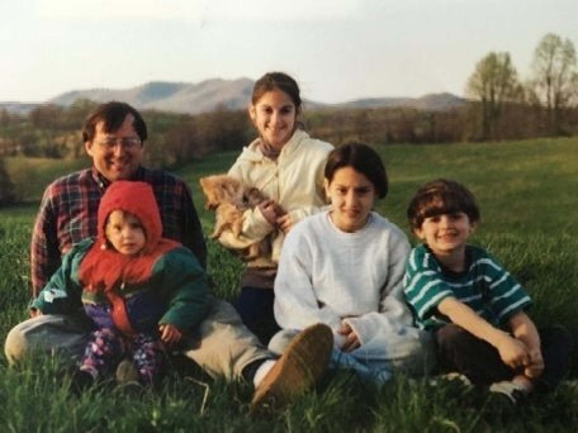 Five children sitting on a hillside lawn with the Blue Ridge Mountains in the background